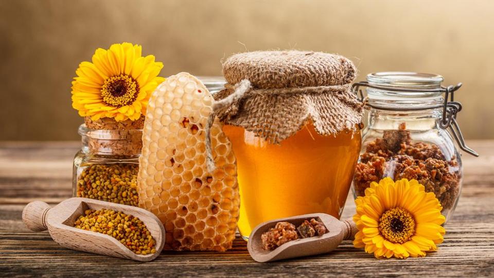 Ένα τραπέζι με ξηρούς καρπούς, κερήθρες, λουλούδια και βάζο γεμάτο μέλι